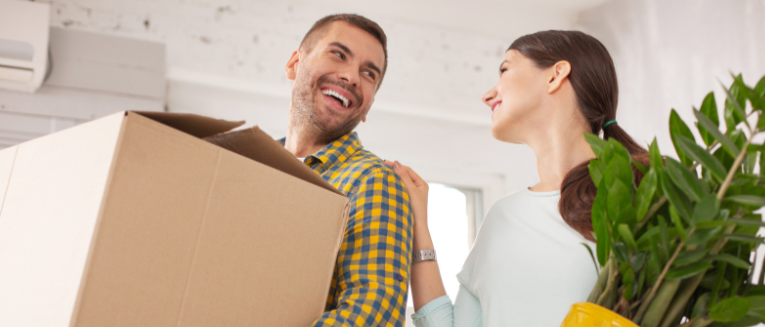 Plant at home. Low angle of happy cheerful couple carrying belongings and talking